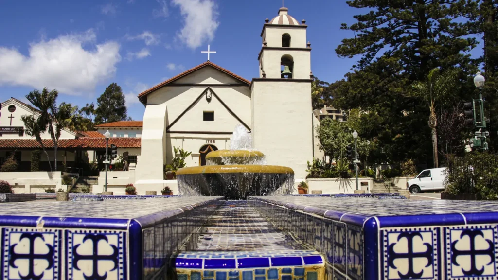 The white Mission San Buenaventura church and bell tower behind a tiled fountain in downtown Ventura