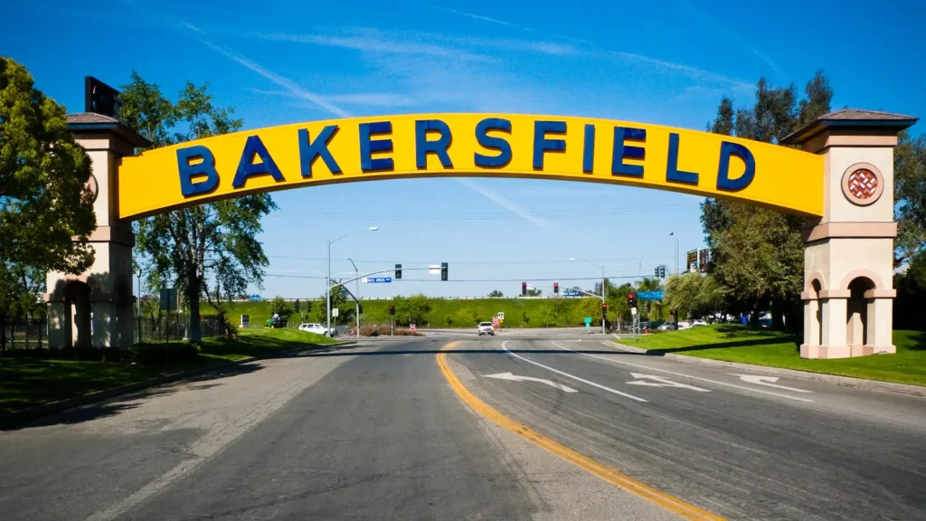 The yellow and blue Bakersfield arch sign spanning a street, with palm trees