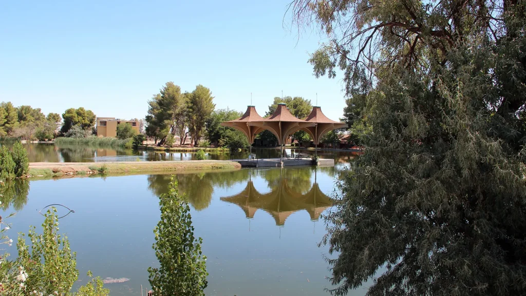 A lake with trees and a pavilion at Central Park in California City