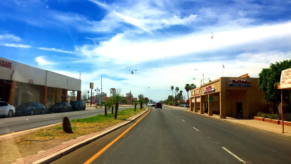 A wide main street with low storefronts and palm trees under a blue sky in downtown Calipatria