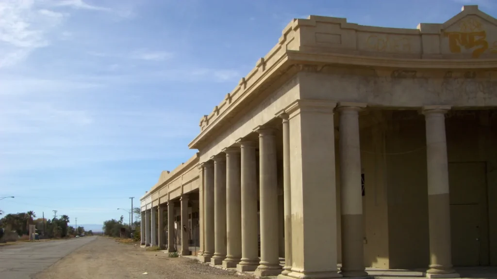 An old commercial building with a row of columns along a dirt street in downtown Niland