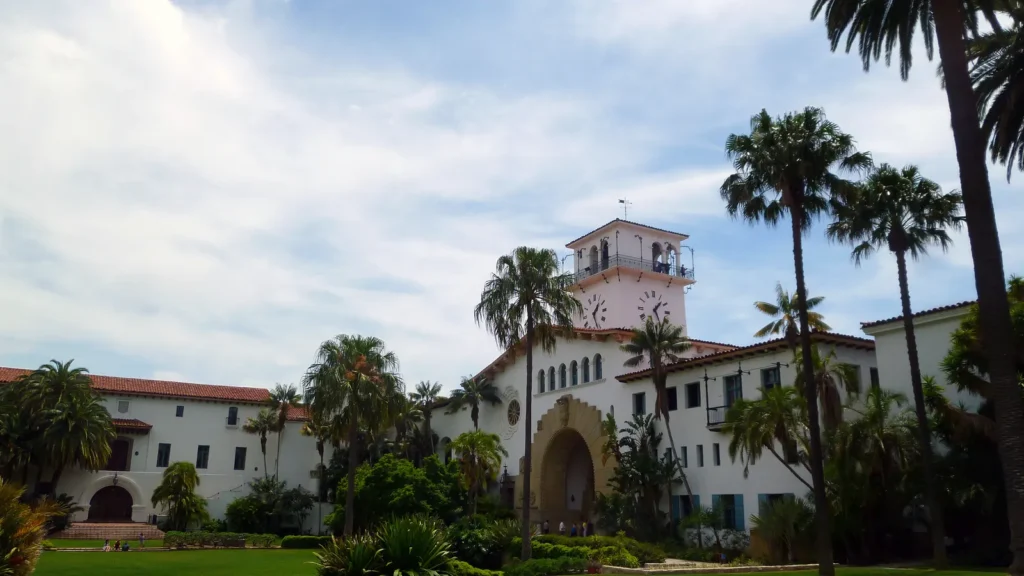 The white Spanish-Revival Santa Barbara County Courthouse with its clock tower, palm trees and a green lawn