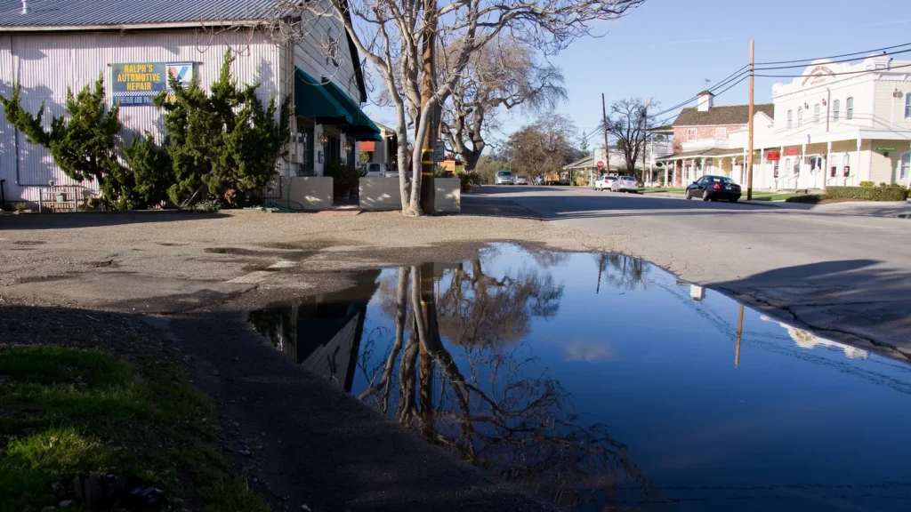 Old storefronts of Santa Ynez reflected in a puddle under a blue sky