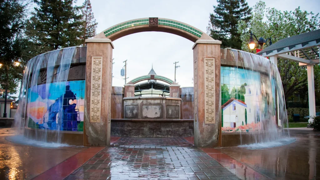 A fountain with an arch and painted murals in Shafter