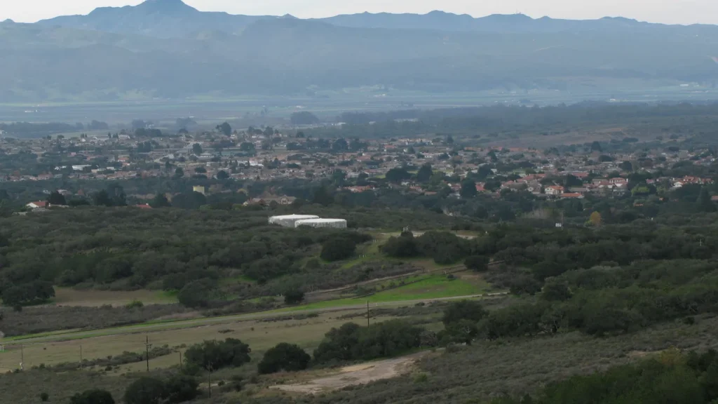 Homes of Vandenberg Village among trees, with hills and mountains behind