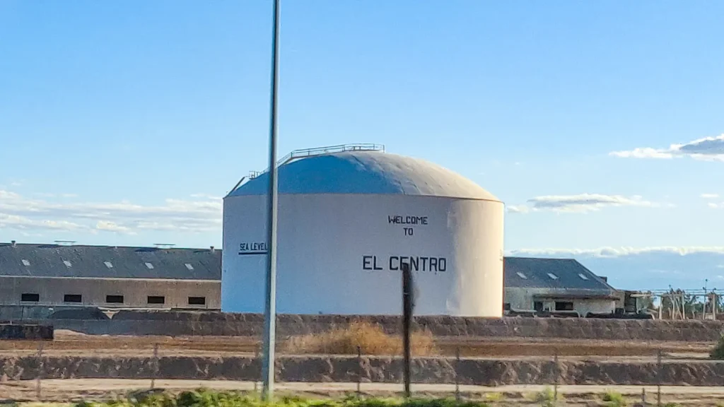 White water tower painted Welcome to El Centro and Sea Level, under a blue sky in El Centro, Imperial County