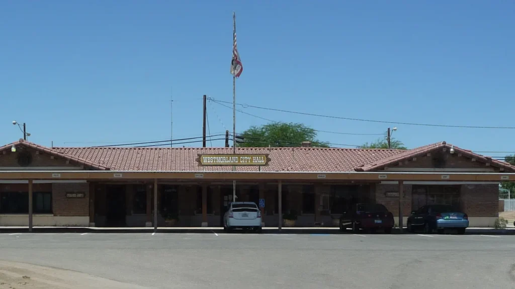 The long, low Westmorland City Hall building with a tiled roof and a flagpole